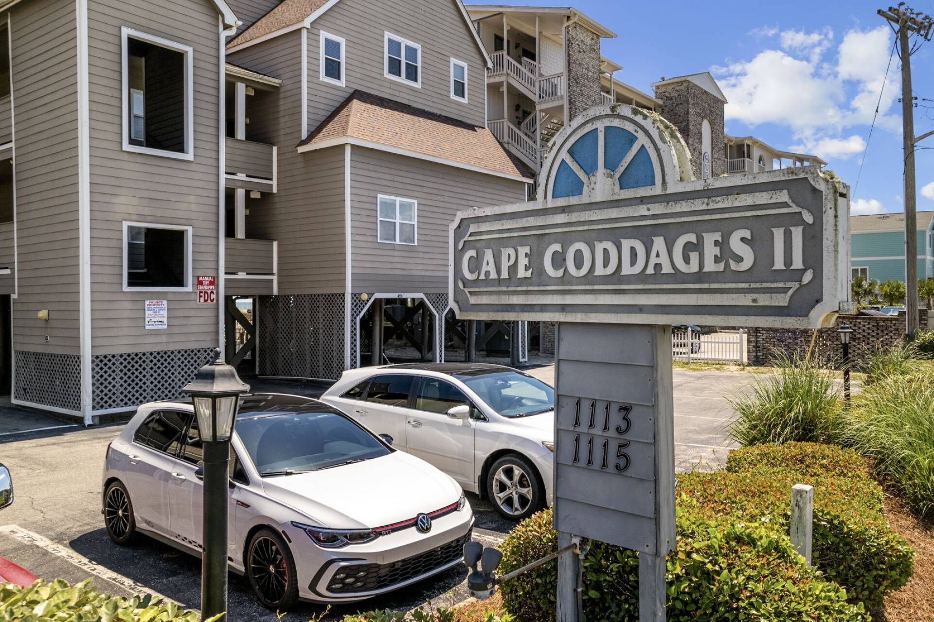 Ein Wohngebäude mit einem Schild, auf dem 'Cape Codges II' steht, und den nummerierten Einheiten 1113 und 1115.