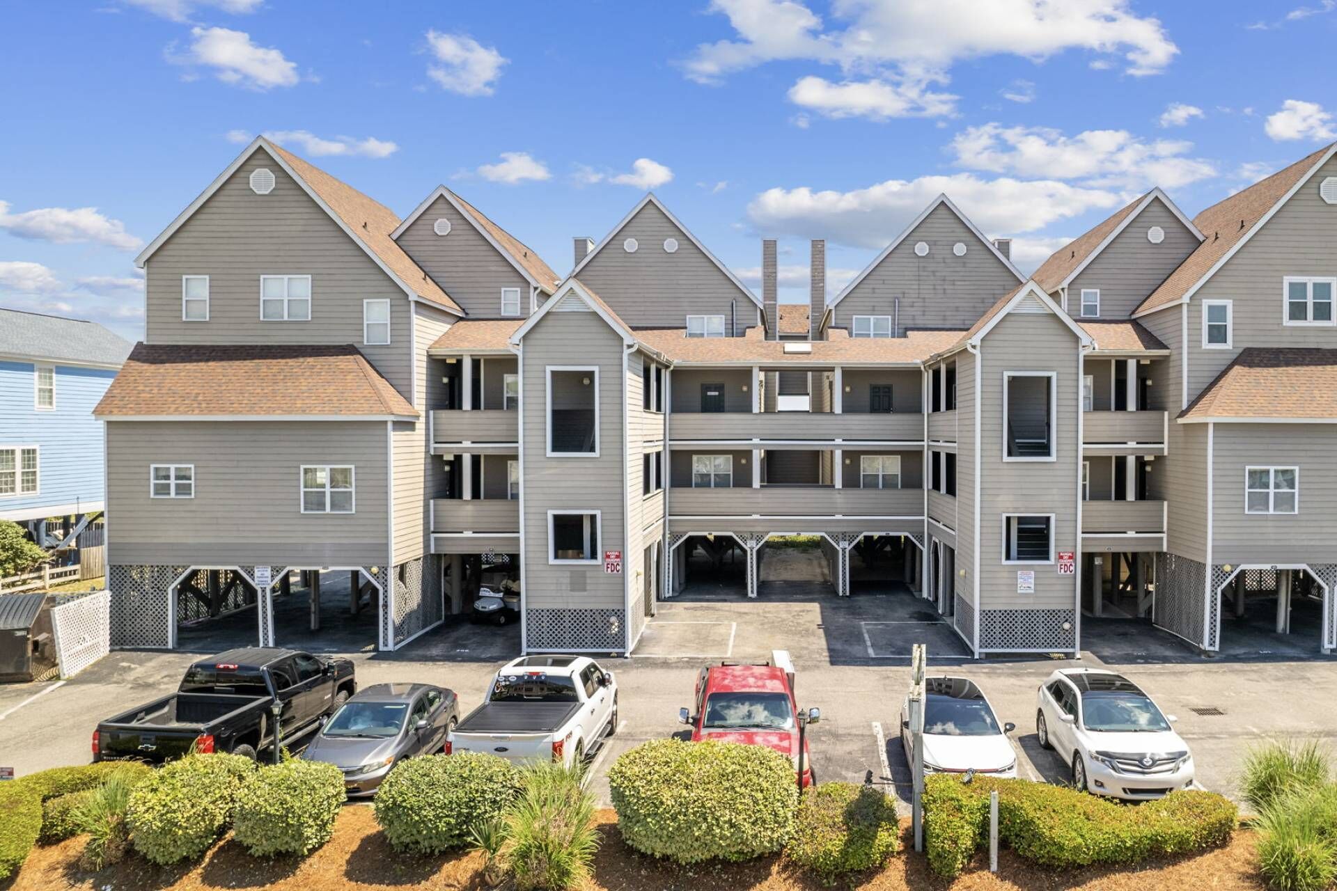 Um edifício residencial com vários andares, garagem central e vários espaços de estacionamento.