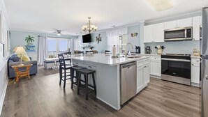 Une cuisine moderne avec des meubles blancs, des appareils en acier inoxydable et un îlot central doté de tabourets de bar.