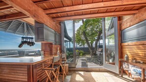 A wooden interior with a bar area, large windows, and a view of the outdoors. - Classic Oceanfront Stinson - The Whale House (Stinson Beach)