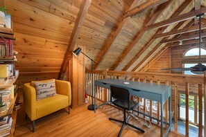Relax in this charming attic room with a sofa, desk, and large window offering a view of the outdoors.