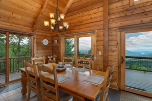 Cozy cabin with a dining area for four, featuring a large table and a chandelier.