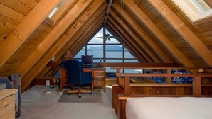 Une chambre confortable située dans les combles, avec un bureau en bois, une chaise, un lit et une vue sur l’eau.