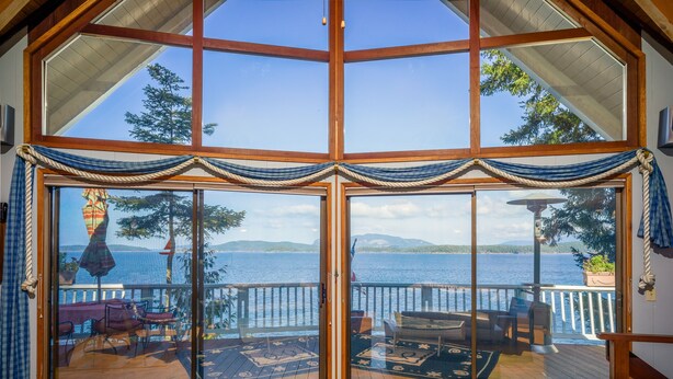 Une grande pièce dotée d’une porte vitrée donnant sur une terrasse avec vue sur la mer.
