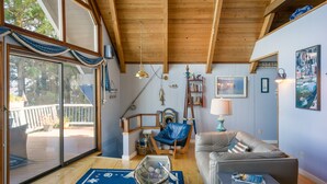 Un salon spacieux avec un plafond en bois, une grande fenêtre et une vue sur l’extérieur.