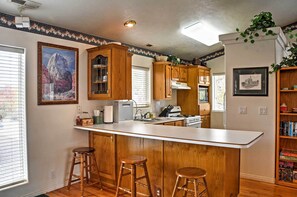 Una cocina con armarios de madera, una isla central con taburetes, un refrigerador y una estufa.