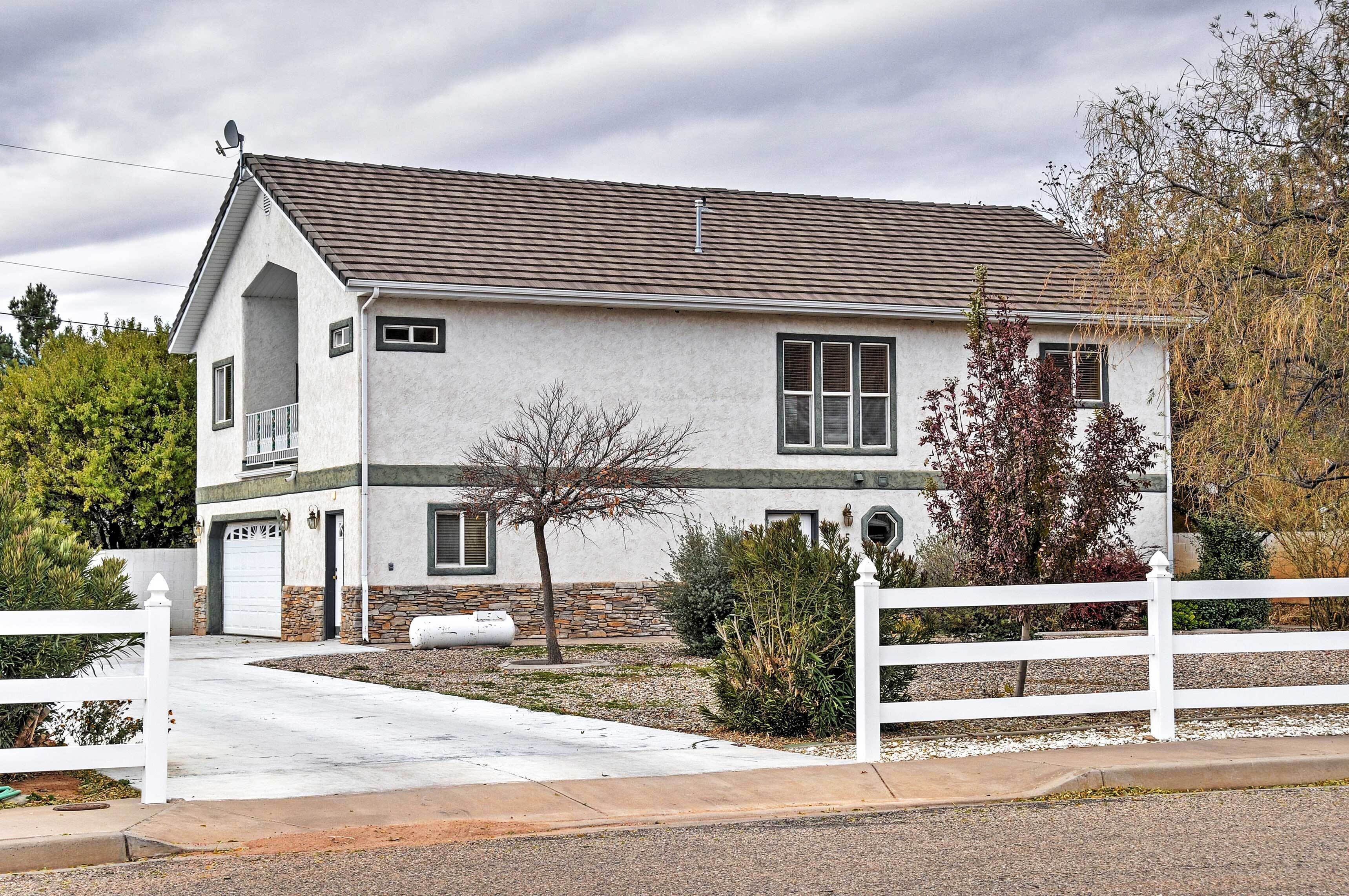 A two-story house with a garage, a satellite dish, and a white picket fence.