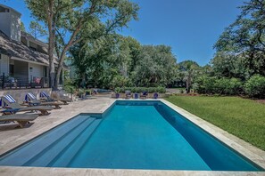 A rectangular swimming pool with lounge chairs and a covered seating area, surrounded by trees and a well-maintained lawn. - 6 High Rigger-2nd Row (20 yards) to the Ocean, Fully Renovated Home w/Pool. (Hilton Head Island)