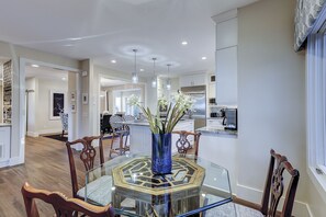 A modern kitchen with stainless steel appliances, a dining area with a glass table and wooden chairs, and a hallway leading to another room. - 6 High Rigger-2nd Row (20 yards) to the Ocean, Fully Renovated Home w/Pool. (Hilton Head Island)