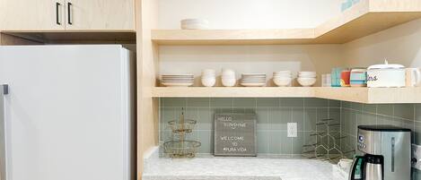 Een moderne keuken met houten kastjes, een witte koelkast, een koffiezetapparaat en een afwasschaal.