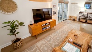 Ein Wohnzimmer mit Fernseher, Holzvertäfelung, einem gemusterten Teppich und einer Pflanze.