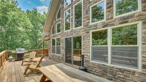 Une terrasse en bois avec un bâtiment en pierre, des sièges d’extérieur et un barbecue.
