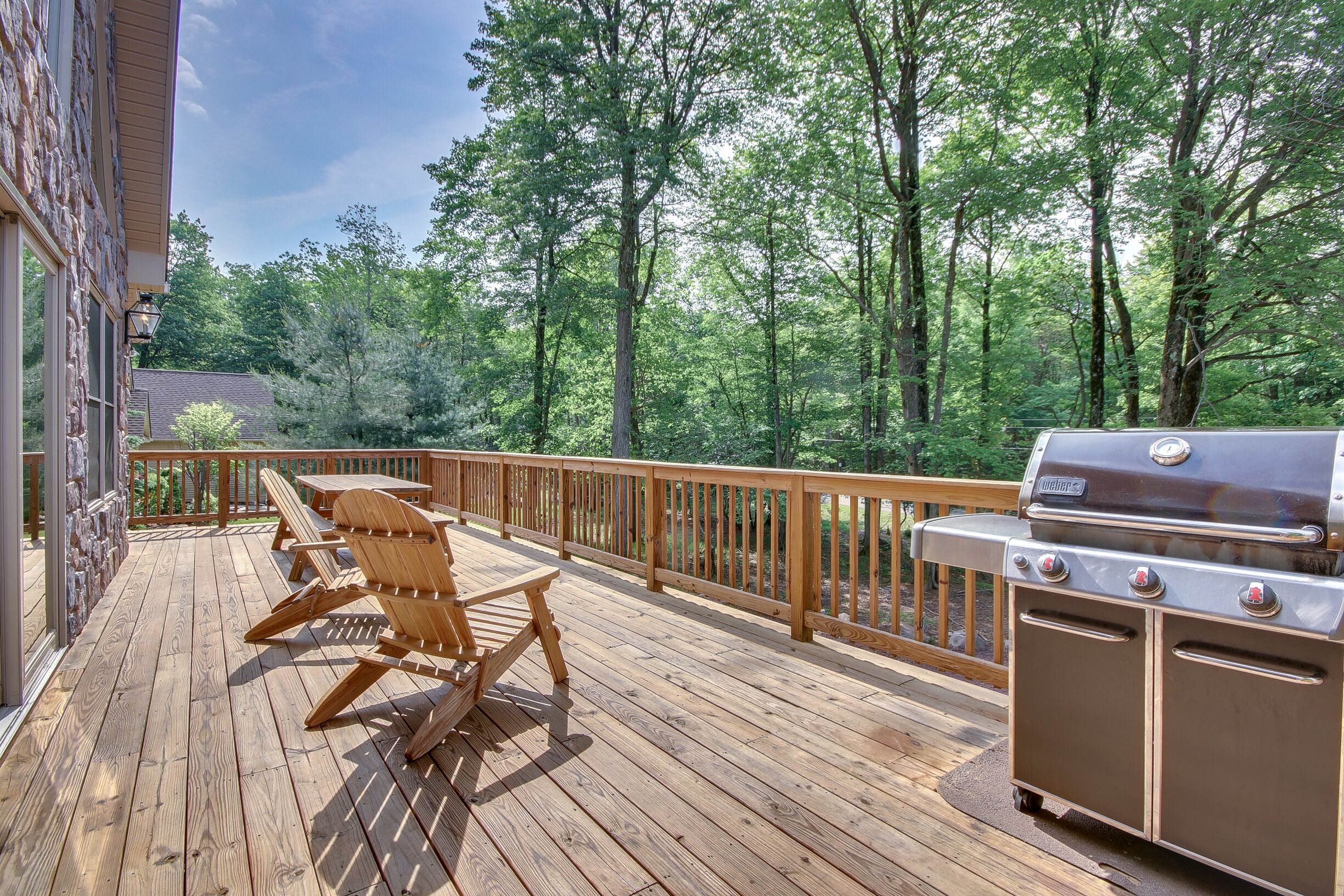 A wooden deck with outdoor furniture and a grill.