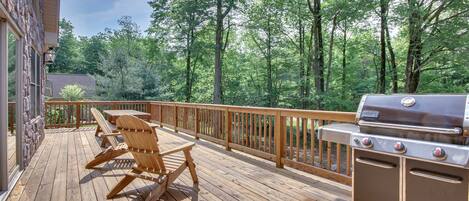 A wooden deck with outdoor furniture and a grill.