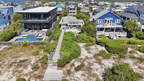 Et kystnært boligområde med huse, en swimmingpool og en træterrasse ned til stranden.