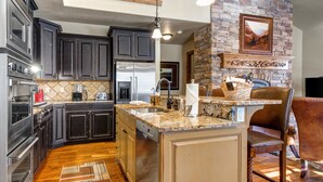 Una cocina moderna con armarios oscuros, electrodomésticos de acero inoxidable y encimera de granito.