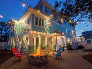 A two-story house with a covered patio area, outdoor seating, and a fire pit.