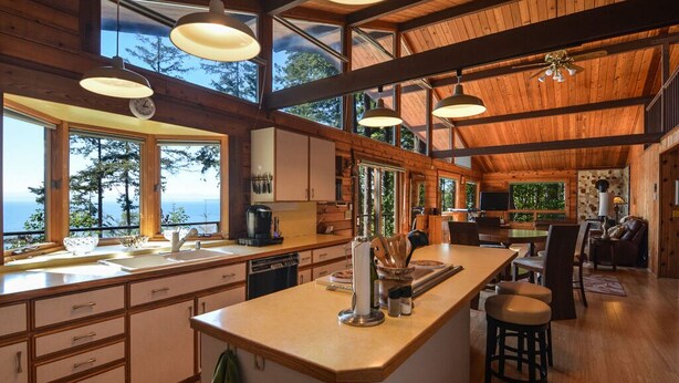 Una cocina amplia con ventanas grandes, vigas de madera y una isla central.