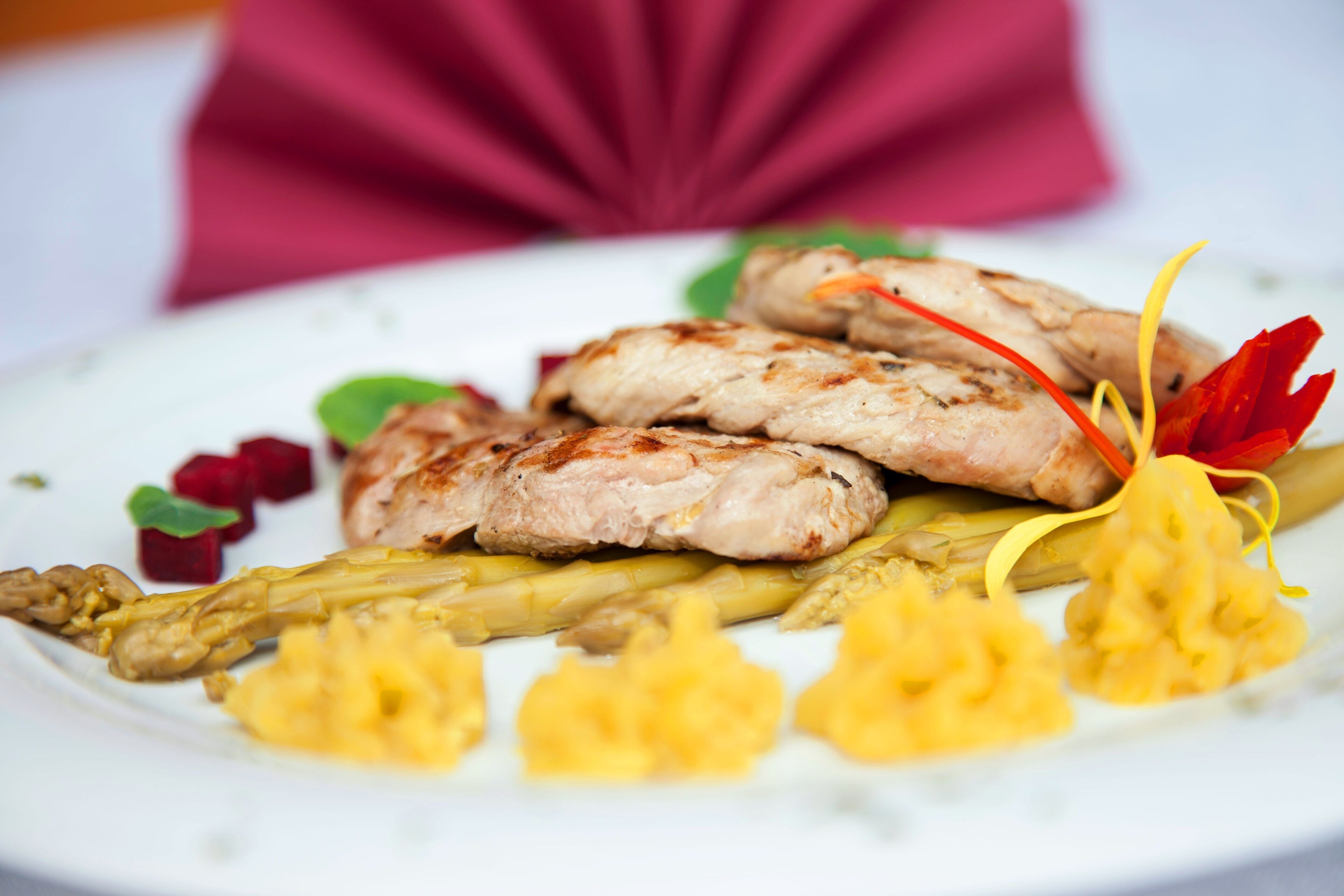 Un plato con pollo a la parrilla, espárragos y una decoración floral.