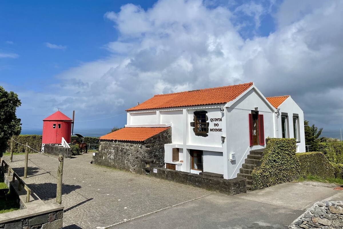 A white building with a red roof and a sign reading "QUINTA DO MOINH."