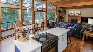 A spacious kitchen with a large island, wooden flooring, and a view of a lake through large windows. - San Juan Island, Neil Bay #800 (Friday Harbor)