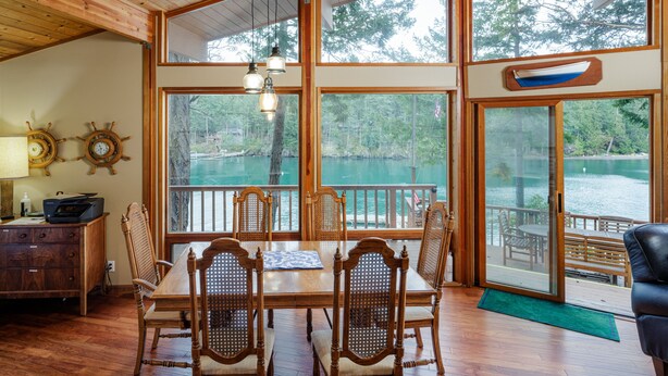 A wooden dining area with a table and chairs, large windows with a view of a lake, and a wooden ceiling. - San Juan Island, Neil Bay #800 (Friday Harbor)