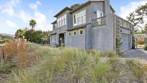 A two-story house with a gray exterior, a front porch, and a garage. - Immaculate Beach House with Great Views Of Mt Tam (Stinson Beach)