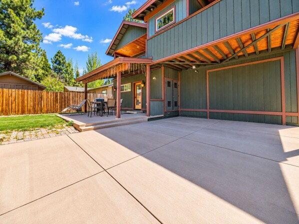 A two-story house with a covered patio, a wooden fence, and a well-maintained lawn.
