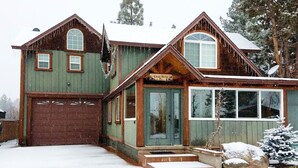 Une cabane en bois avec un garage, de grandes fenêtres et une enseigne sur laquelle on peut lire « Casa Bella ».