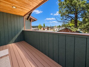 A wooden deck with a view of a residential area and a pine tree.