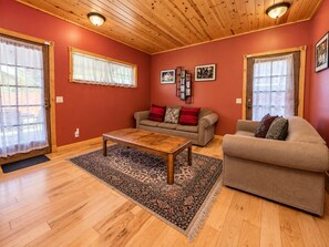 A living room with a wooden ceiling, a sofa, a coffee table, and a rug.