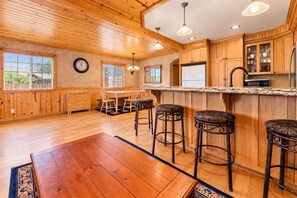 A spacious kitchen with wooden cabinets, a central island with stools, and a large window providing natural light.