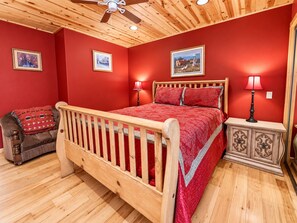A bedroom with a wooden bed, red walls, and a ceiling fan.