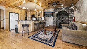 Une cuisine spacieuse avec des meubles en bois, une cheminée en pierre et un coin bar.