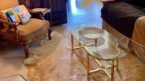 A cozy living room with a wooden wall, a glass coffee table, a leather sofa, and a wooden chair. - Palm Desert Resort & Country Club I (Palm Desert)