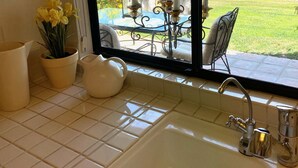 A kitchen with a large window, a sink, and potted plants. - Palm Desert Resort & Country Club I (Palm Desert)