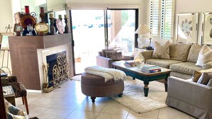 A spacious living room with a fireplace, comfortable seating, and a view through a glass door. - Palm Desert Resort & Country Club I (Palm Desert)