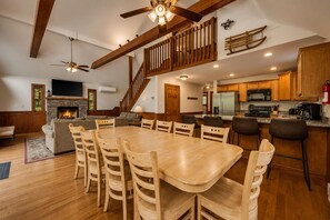 A spacious living area with a fireplace, wooden dining table, and a kitchen with modern appliances.
