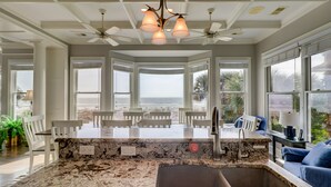 A spacious kitchen with a large island, a built-in sink, and a view of the beach.