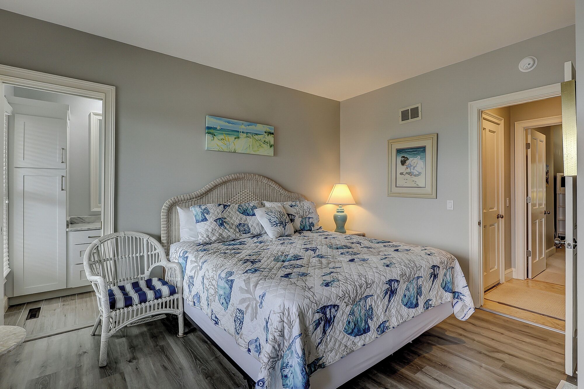 A bedroom with a bed, a chair, a lamp, and artwork on the walls.