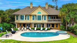 A two-story house with a large backyard, a swimming pool, and outdoor seating.