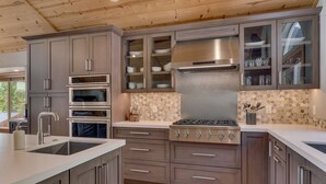 Een moderne keuken met inbouwovens, een roestvrijstalen kookplaat en een spatwand met honingraatmozaïek.