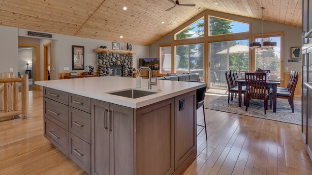 Een ruime keuken met een groot eiland, houten plafond en grote ramen met uitzicht op de omgeving.