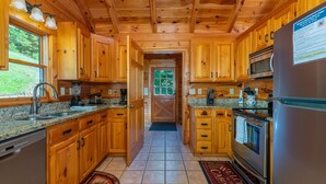 Een houten keuken in een chalet met granieten aanrechtbladen, houten kastjes, een roestvrijstalen koelkast en een inbouwoven.