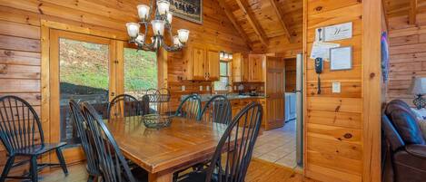 Interior de una cabaña de madera con comedor, cocina y sala de estar.