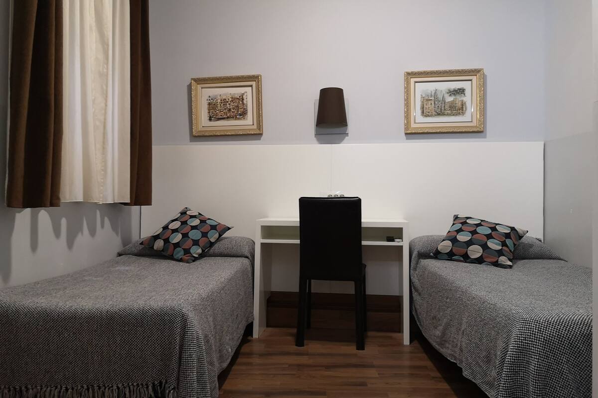Un dormitorio con dos camas individuales, un escritorio y una silla.