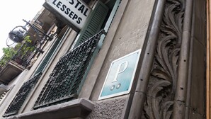 Un edificio con un cartel que dice "HOSTAL LESSEPS" y un letrero de estacionamiento con la letra "P".