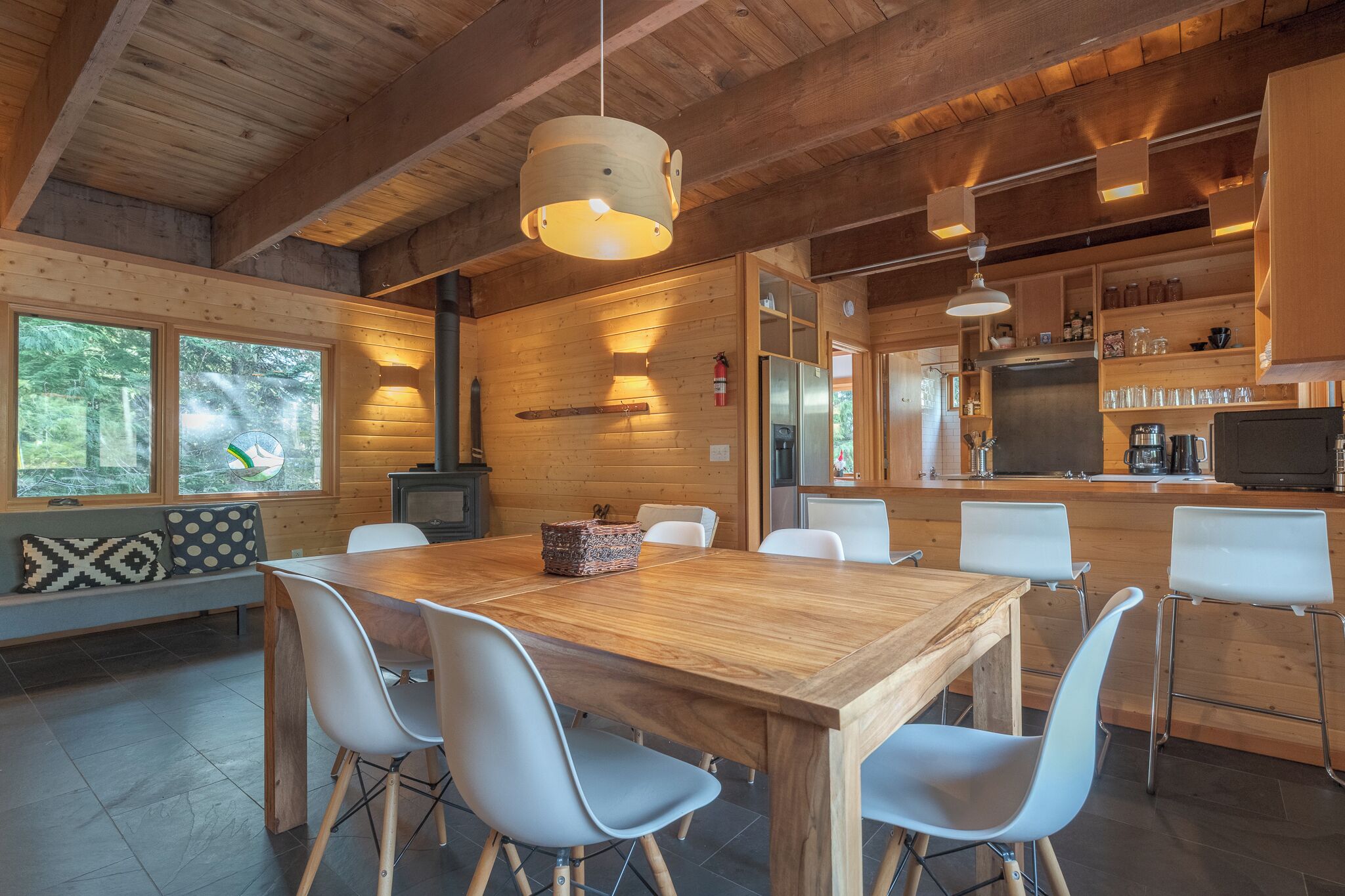 Ein Holzinterieur mit Essbereich, Küche und großen Fenstern.