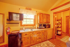 Una cocina con armarios de madera, un microondas integrado y un lavamanos.
