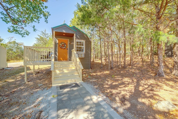 A small wooden cabin with a porch and steps leading to the door.